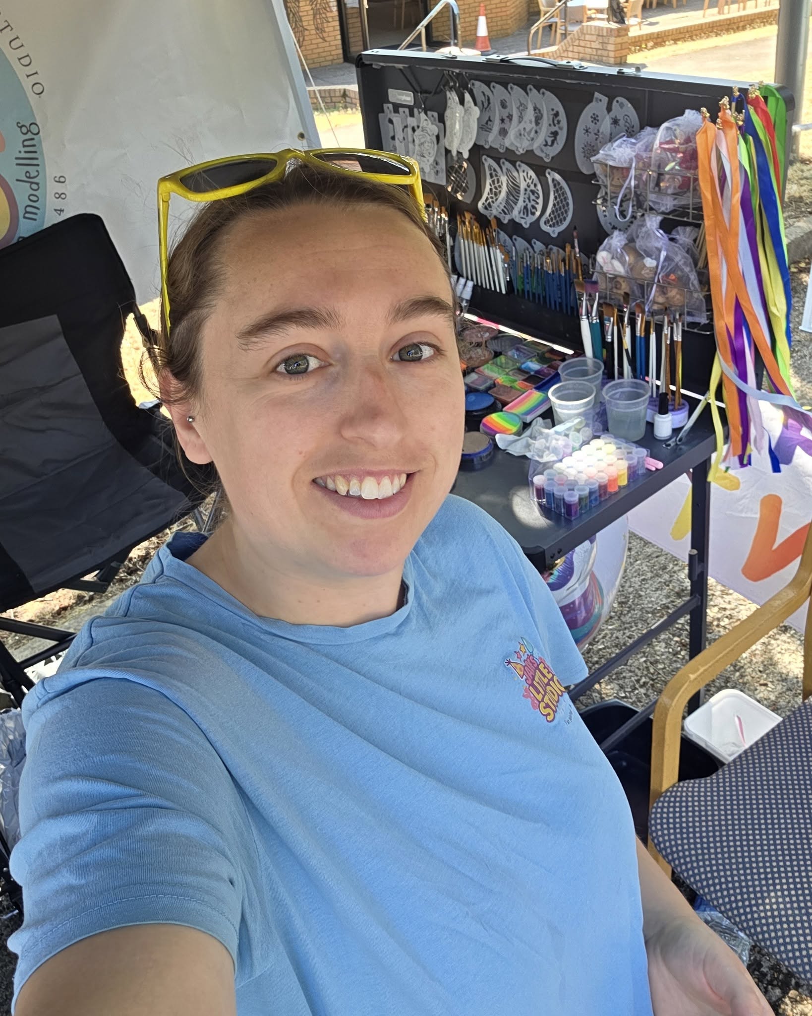 Jade smiling at an event beside her face paints, brushes and colourful ribbons